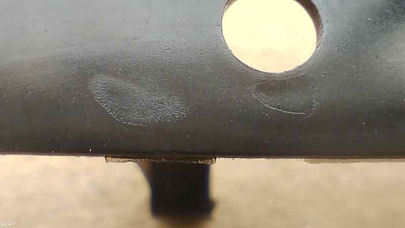 Close-up shot of a thin-walled plastic part showing discoloration spots and rough surface texture.