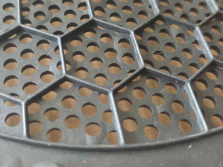 Close-up back side of round PP plastic speaker cover showing smooth surface without rounded hole edges