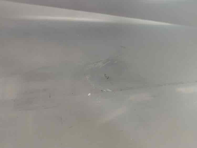 Close-up showing surface scratches and a dent on the stainless steel tray.