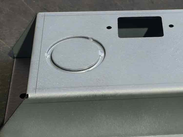 Close-up showing a knockout in a push button enclosure with three points connected, ready to be removed.