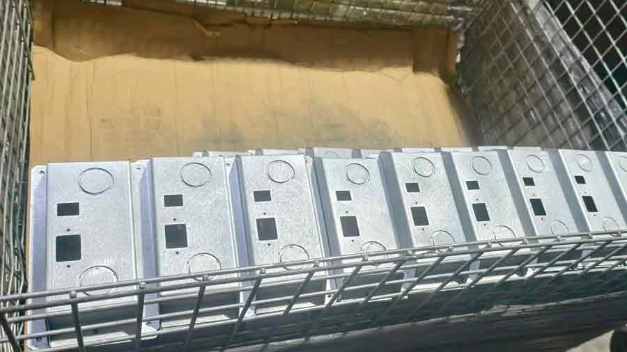 Multiple push button enclosures neatly arranged in a metal basket, showcasing consistent surface quality and dimensions.
