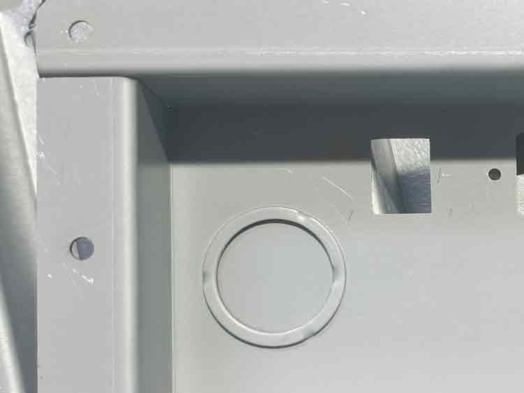 Close-up showing a light scratch on the surface of electro galvanized steel during the stamping process, with the knockout visible.