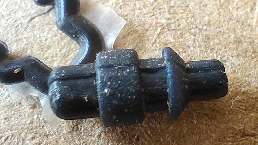 Close-up of a small black silicone part from the custom plastic toy showing minor flash after compression molding, demonstrating high molding precision
