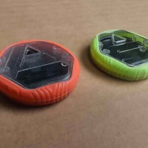 Assembled custom plastic toy with injection-molded plastic body, transparent top, and silicone sleeve in red and green colors.