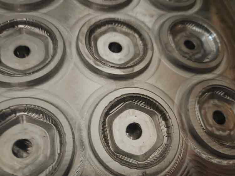 Close-up of the silicone compression mold cavities showing the tire-like outer texture pattern for the silicone sleeve of the custom plastic toy.