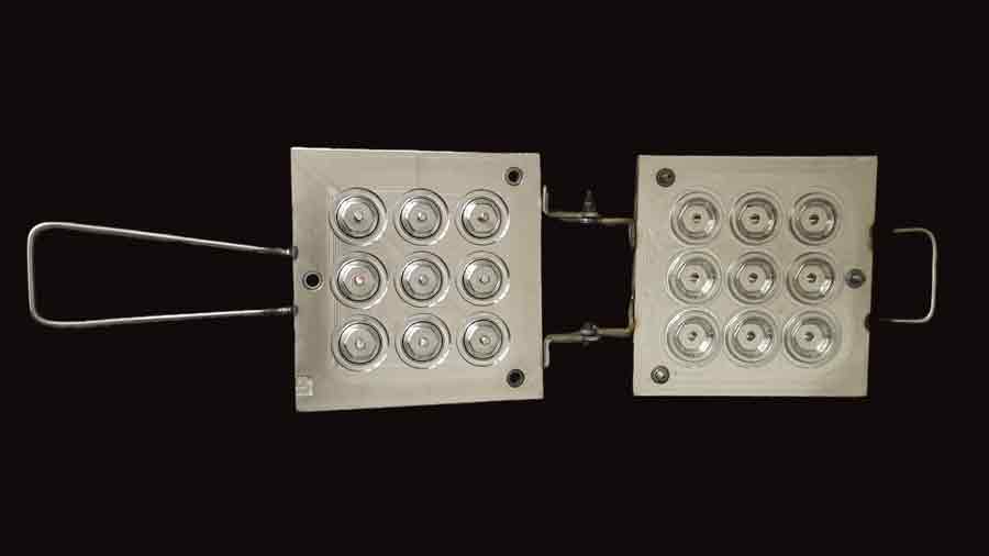 Nine-cavity silicone compression mold used to produce the outer sleeve of the custom plastic toy, featuring tire-like surface patterns on each cavity.