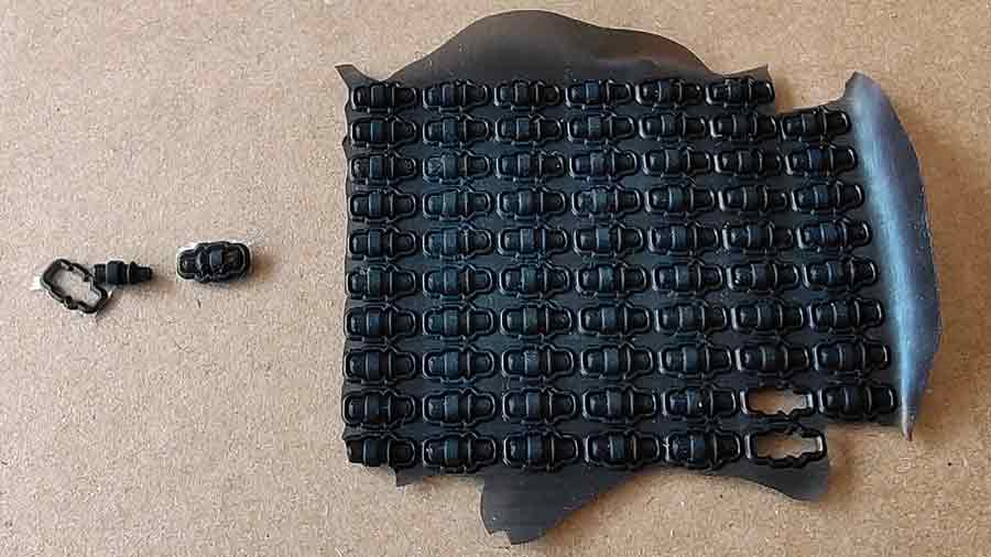 Black silicone parts from the custom plastic toy produced in a high-cavity compression mold, showing fine surface details and manual deflashing process.