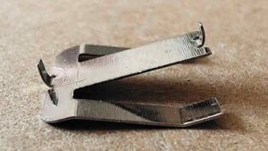 Close-up of a small stainless steel stamped part from the custom plastic toy showing fine semi-circular slots and small bending details made with precision dies.