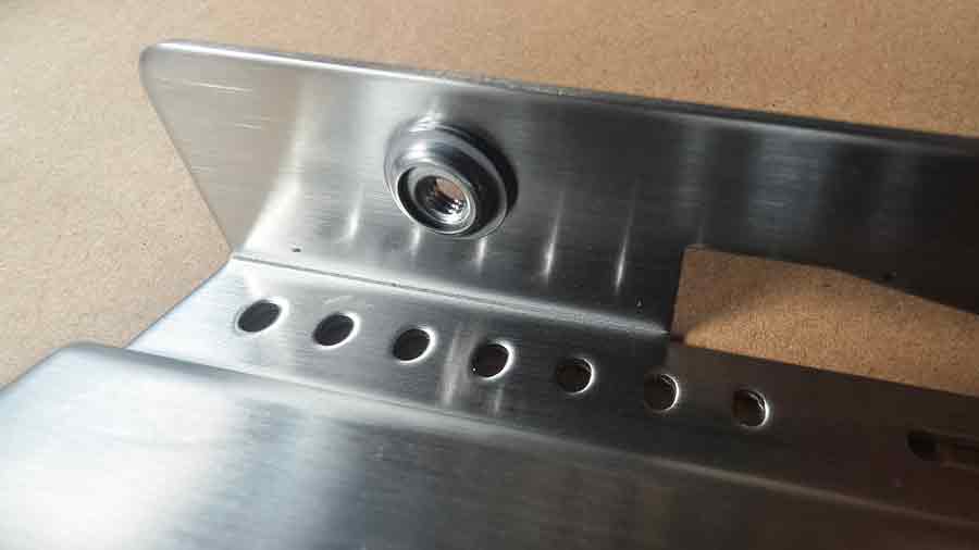 Vue arrière rapprochée d'un insert d'écrou flottant sur un emboutissage en acier inoxydable, montrant la zone surélevée autour de l'insert pour une fixation auto-agrippante sûre.