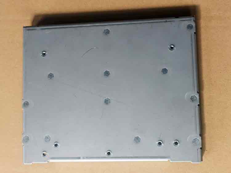 Vista inferior de la pieza estampada a medida, mostrando la parte posterior de las tuercas autofrenantes y su fijación a la chapa.