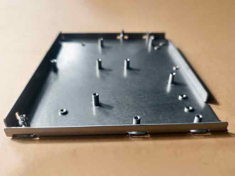 Vue latérale avant d'une pièce emboutie sur mesure avec des écrous auto-agrippants, offrant un aperçu plus clair de la forme et du design.