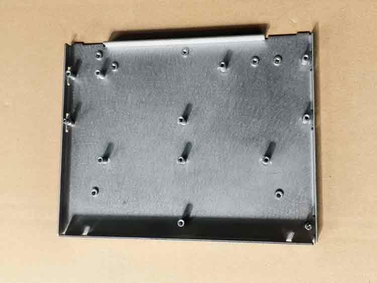 Vista superior de una pieza estampada a medida con tuercas a presión, que muestra la disposición de las tuercas autofijables y los orificios.