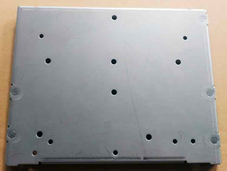 Texte Alt : Vue inférieure d'une pièce emboutie sur mesure avec plusieurs trous ronds avant le processus d'emmanchement, montrant la disposition des trous pour les écrous emmanchés.